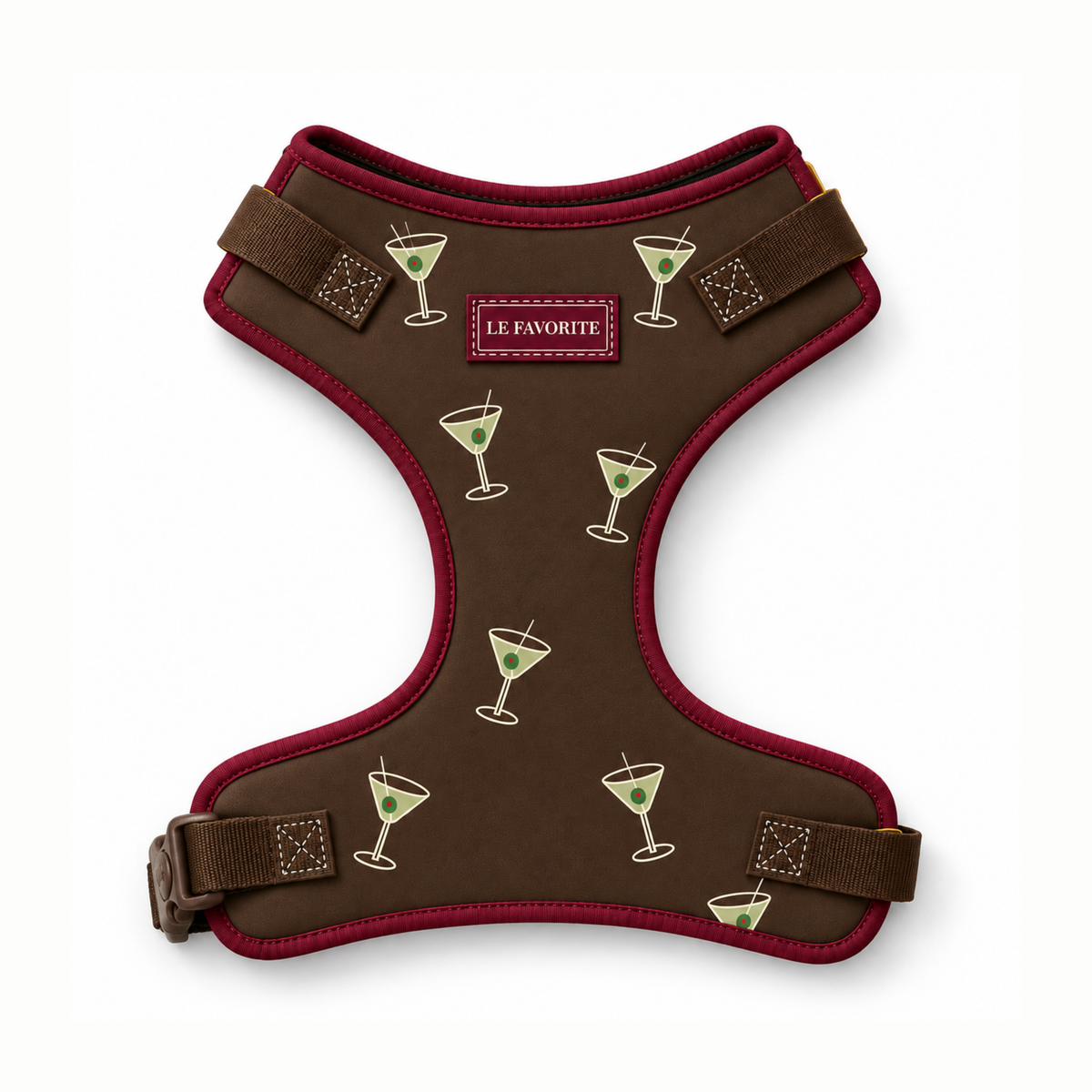 A brown dog harness with dark red trim, featuring a pattern of martini glasses with olives and a central 'LE FAVORITE' brand patch, shown on a white background.