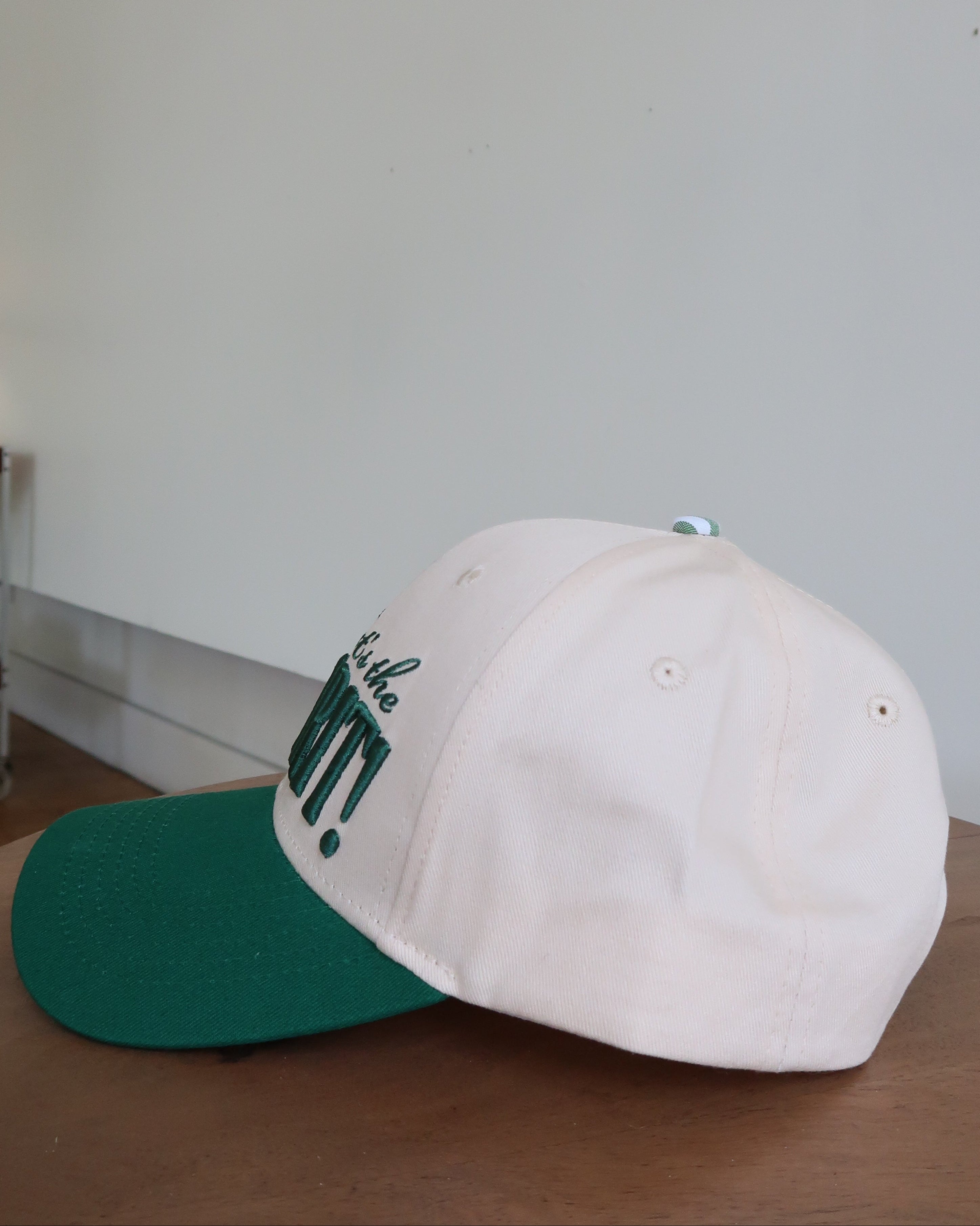 Baseball cap with green brim and white front on a wooden surface