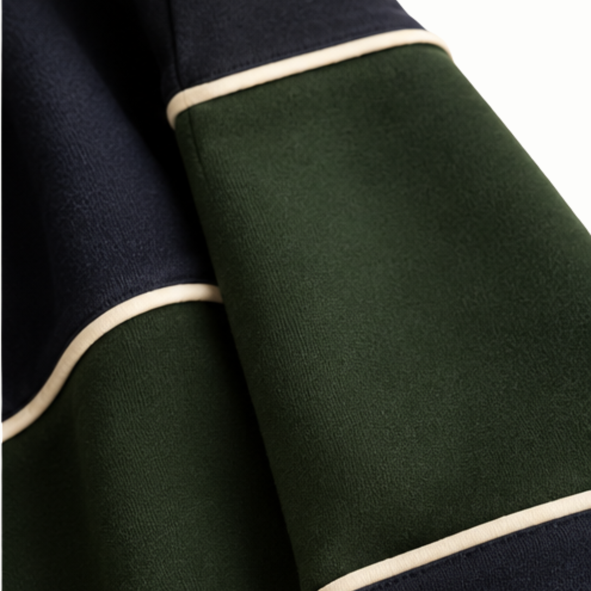Close-up of a ribbed knit garment showing dark green and navy blue color-blocked sections separated by thin cream piping.